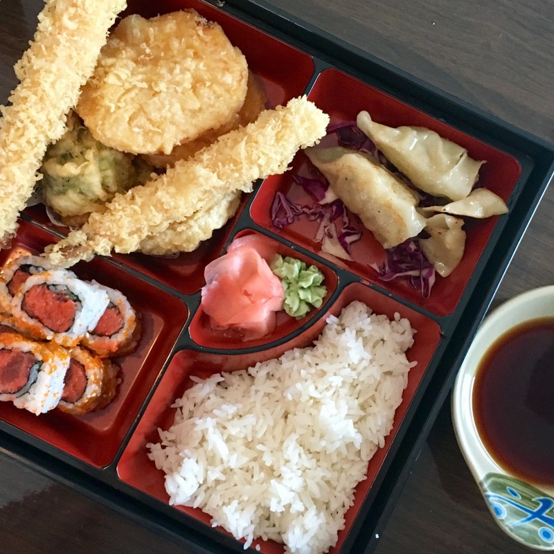 bento box with vegetable tempura, sushi, white rice, gyoza
